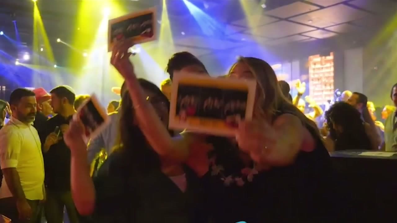 Guests holding TallyBooth photo strips on the dance floor at the end of a Tallahassee reception