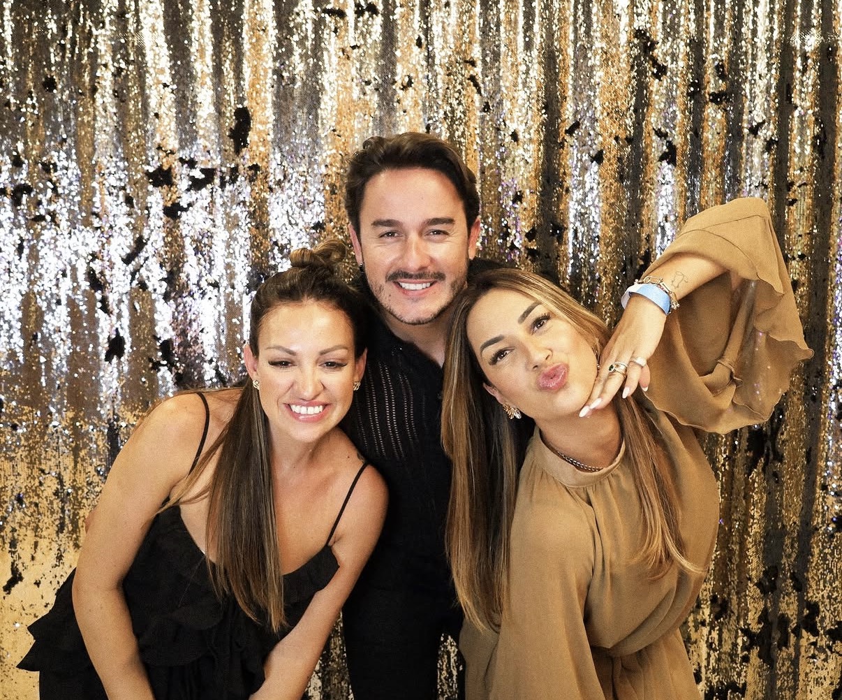 Friends posing at photo booth with gold sequin backdrop