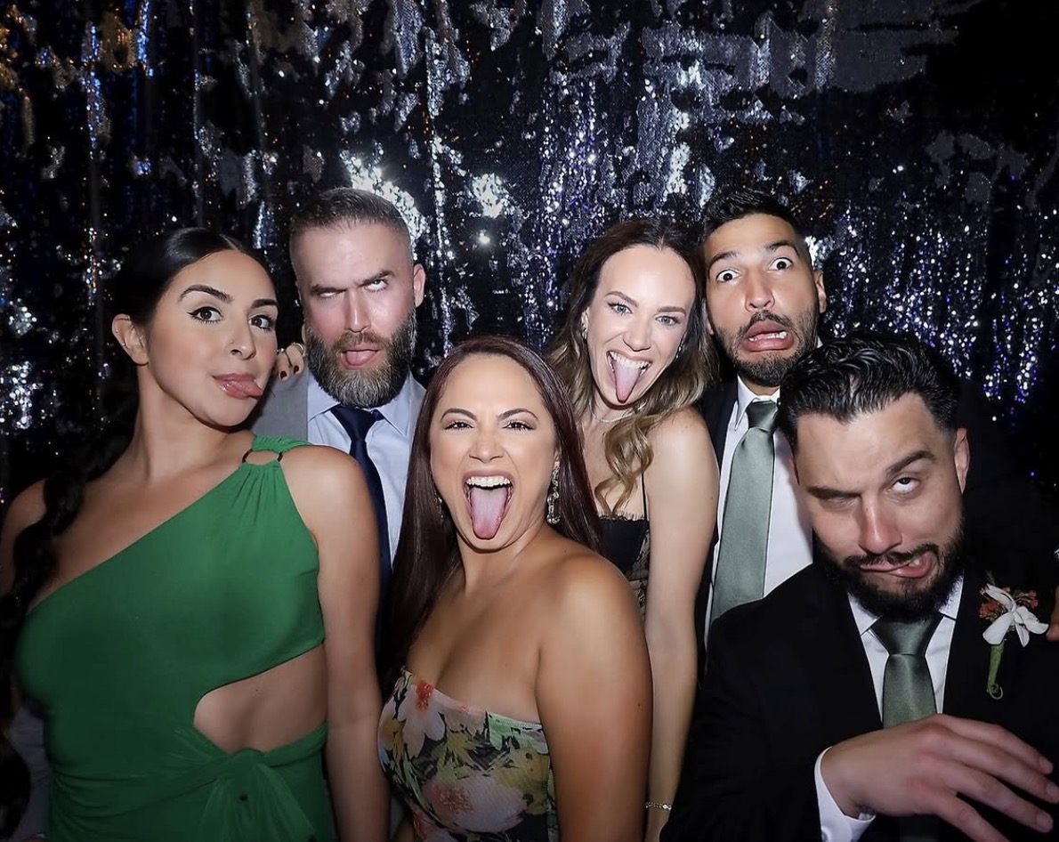 Wedding guests making silly faces at shimmer backdrop photo booth